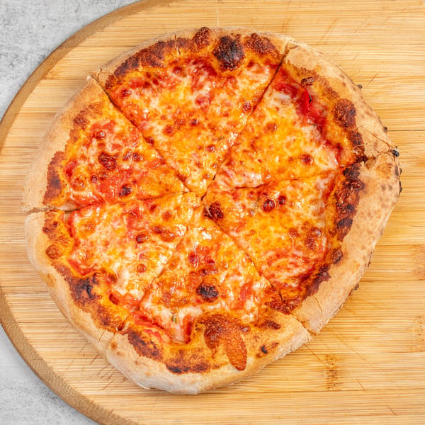 A freshly baked, sliced cheese pizza with a golden crust on a wooden cutting board.